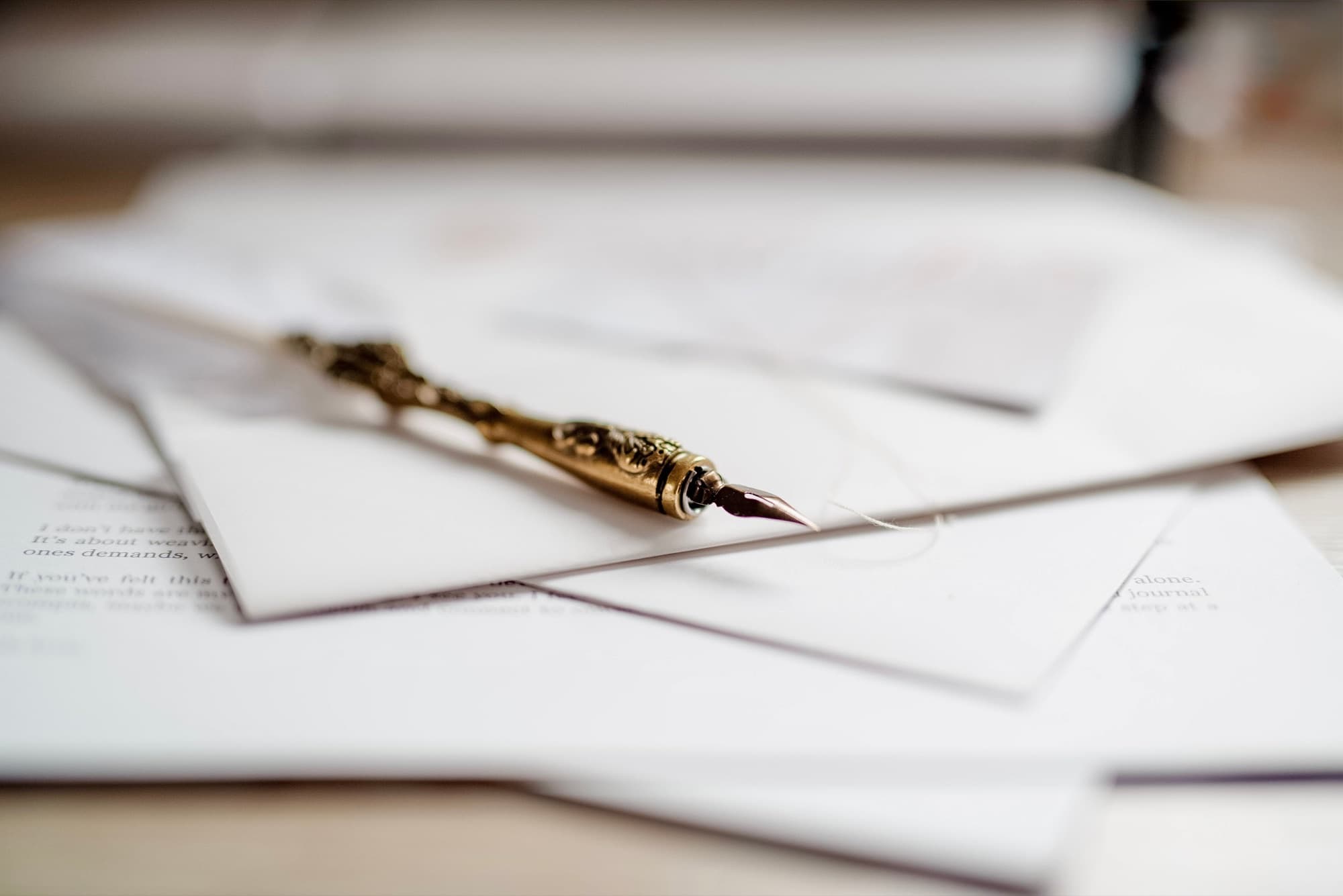 A gold fountain pen resting on handwritten letters